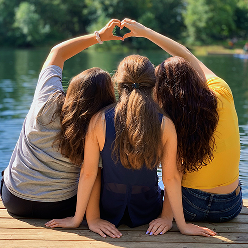 three girls sitting on a dock