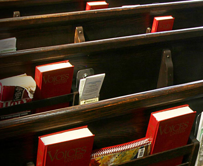 back of church pews with red hymn books